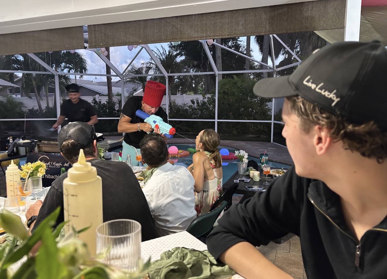 Guests watching a hibachi chef cook at the grill during a private dinner party on a screened patio in Atlantic Beach, Florida