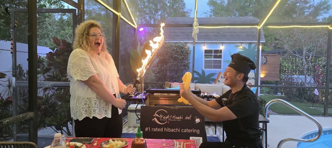 Hibachi chef and a laughing guest holding flaming torches together at a poolside party in Oviedo, Florida