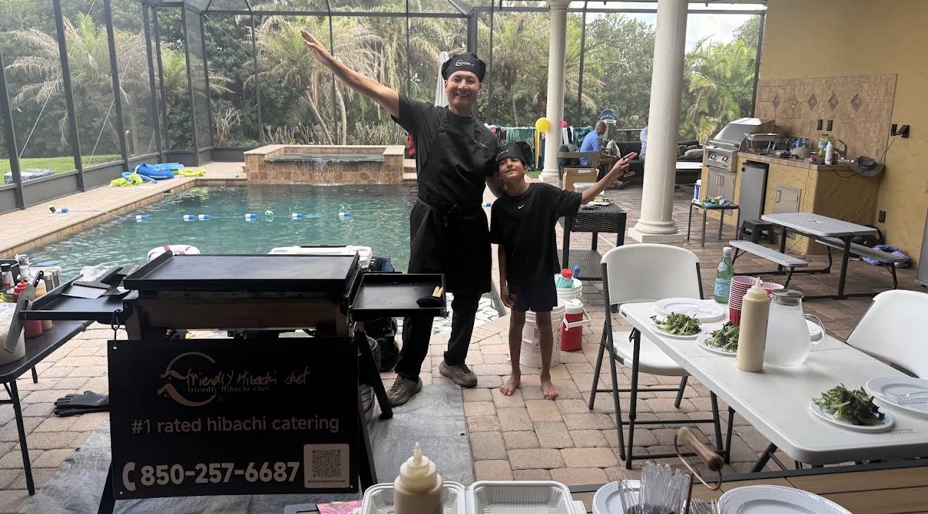 Hibachi chef and a young guest posing by the grill at a poolside backyard party in Fruit Cove, Florida