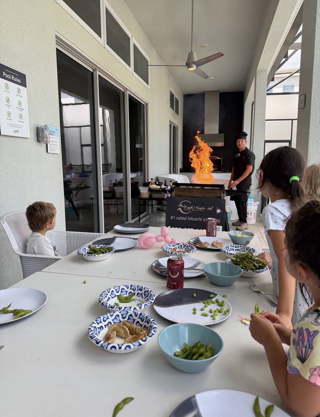 Family with kids watching a hibachi chef fire show during a private dinner at home in St. Augustine, Florida