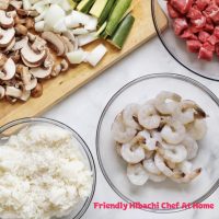 Fresh ingredients for a hibachi regular dinner - raw shrimp, diced steak, mushrooms, onions, zucchini, and rice