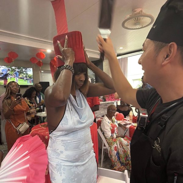 Hibachi chef playfully placing a tall red chef hat on a smiling guest at a private party in Dunedin, Florida