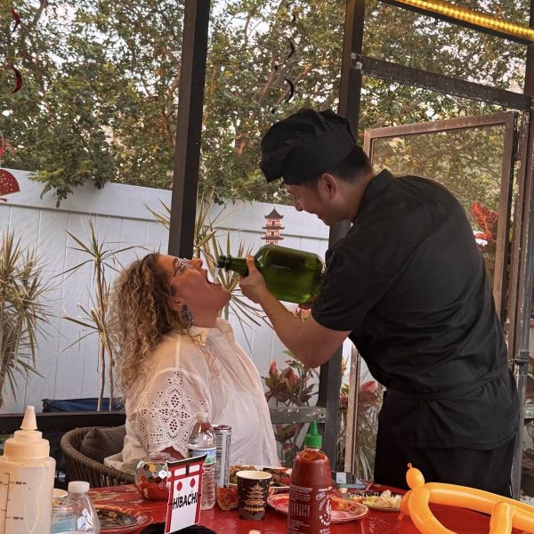 Hibachi chef performing a sake pour trick for a laughing guest at an outdoor private party in Fort De Soto, Florida