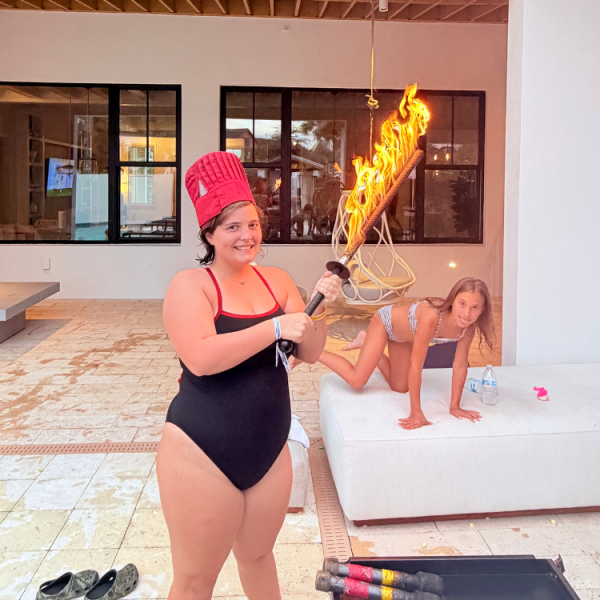 Happy guest wearing a red chef hat and holding a flaming torch at a poolside hibachi party in Fort De Soto, Florida