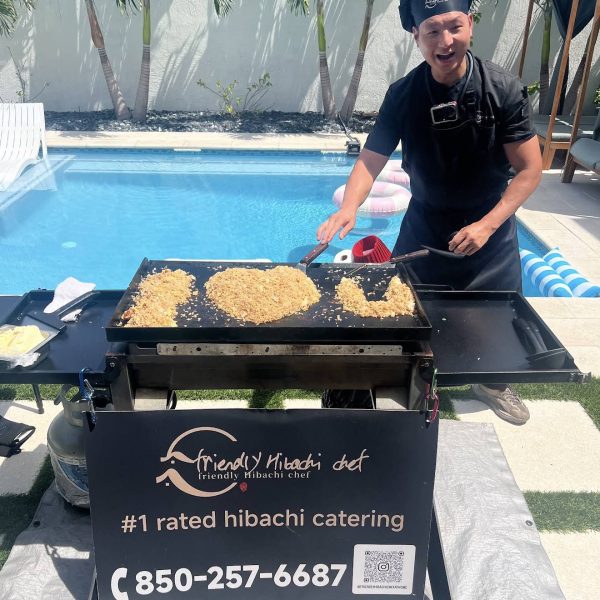 Hibachi chef cooking fried rice on the grill by a pool with palm trees in Clearwater Beach, Florida