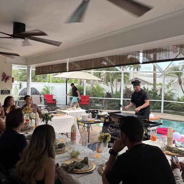 Group of guests seated at tables watching a hibachi chef cook at a poolside dinner party in Dunedin, Florida
