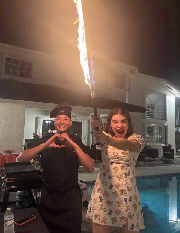 Hibachi chef and a guest making heart gestures with a flaming torch at a nighttime poolside party in Riverview, Florida