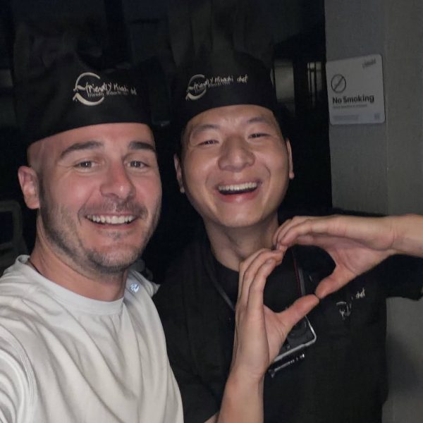 Friendly hibachi chef taking a happy selfie with a guest, making a heart gesture, in Riverview, Florida