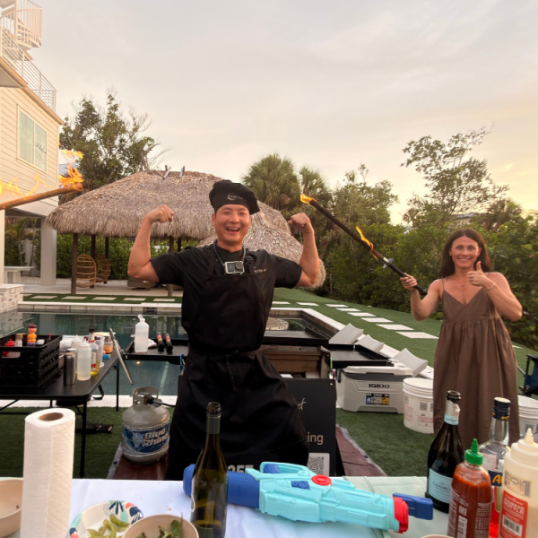 Hibachi chef and a happy guest posing playfully with spatulas at a backyard party in Riverview, Florida